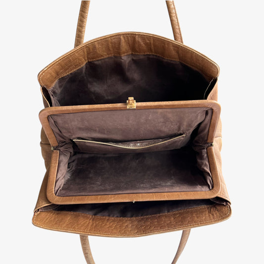 Internal pockets of vintage 1950s crocodile embossed light brown leather shoulder bag on a white background.