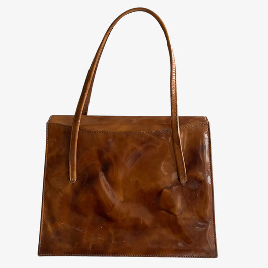 Back of vintage 1960s misty cognac brown faux leather flap on a white background.