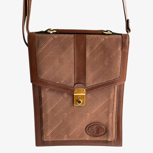 Close up monogram print on the canvas body of a vintage 1970s brown crossbody messenger bag.