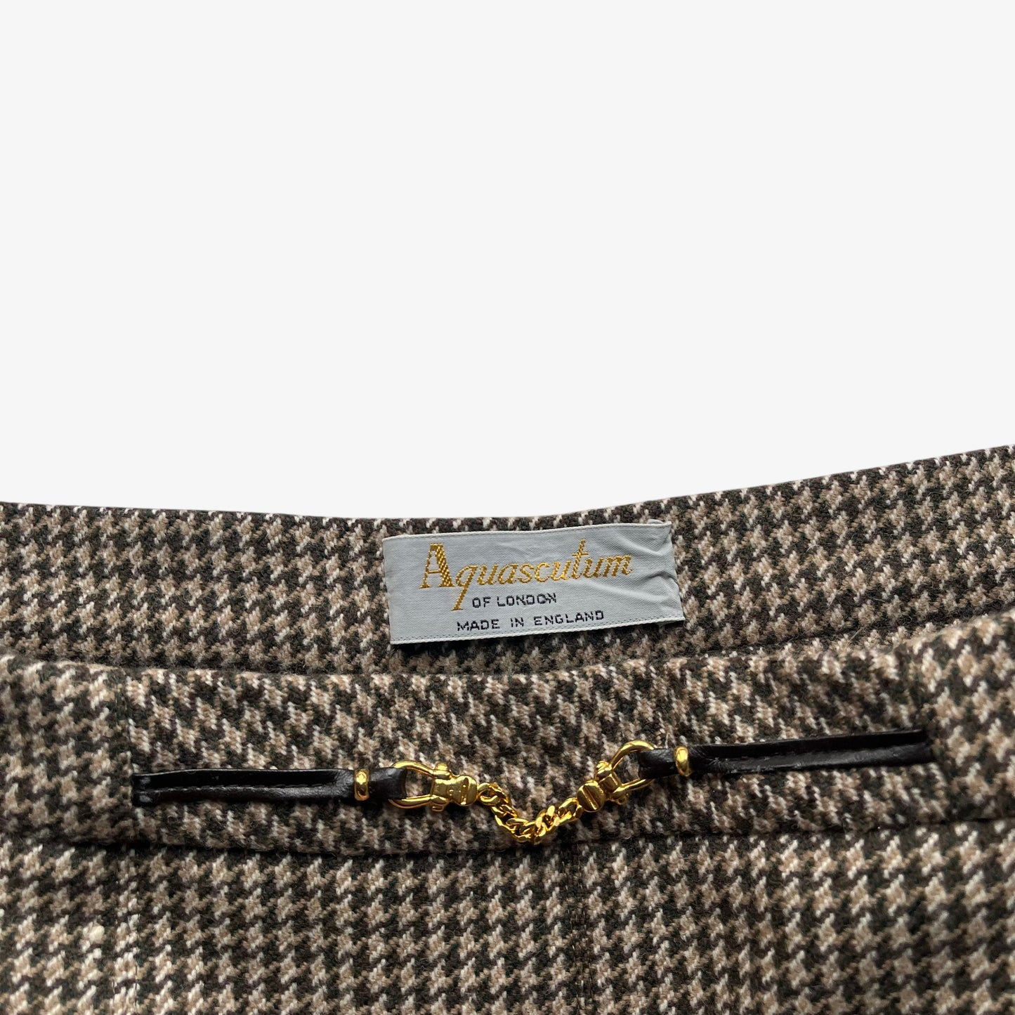 Close up of a houndstooth patterned skirt with a visible Aquascutum label on a white background.