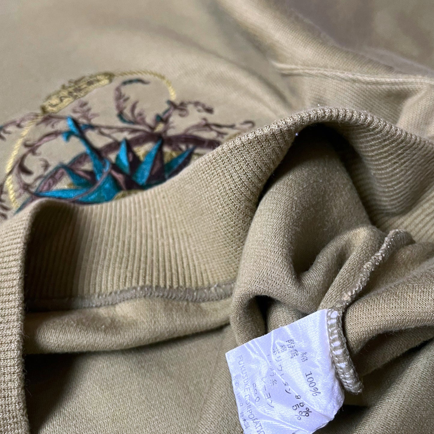 Inside label on vintage 90s men's Lancel Paris green sweatshirt with embroidered nautical pattern.