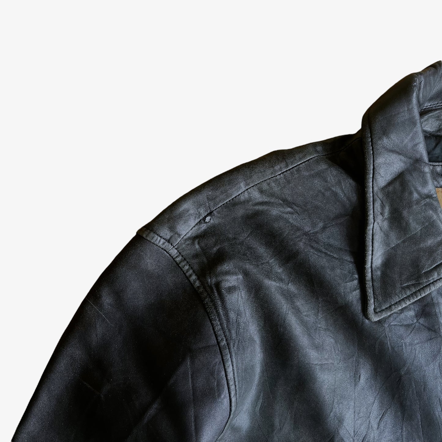 Scuff on the shoulder of a vintage 90s men's Timberland black leather jacket.