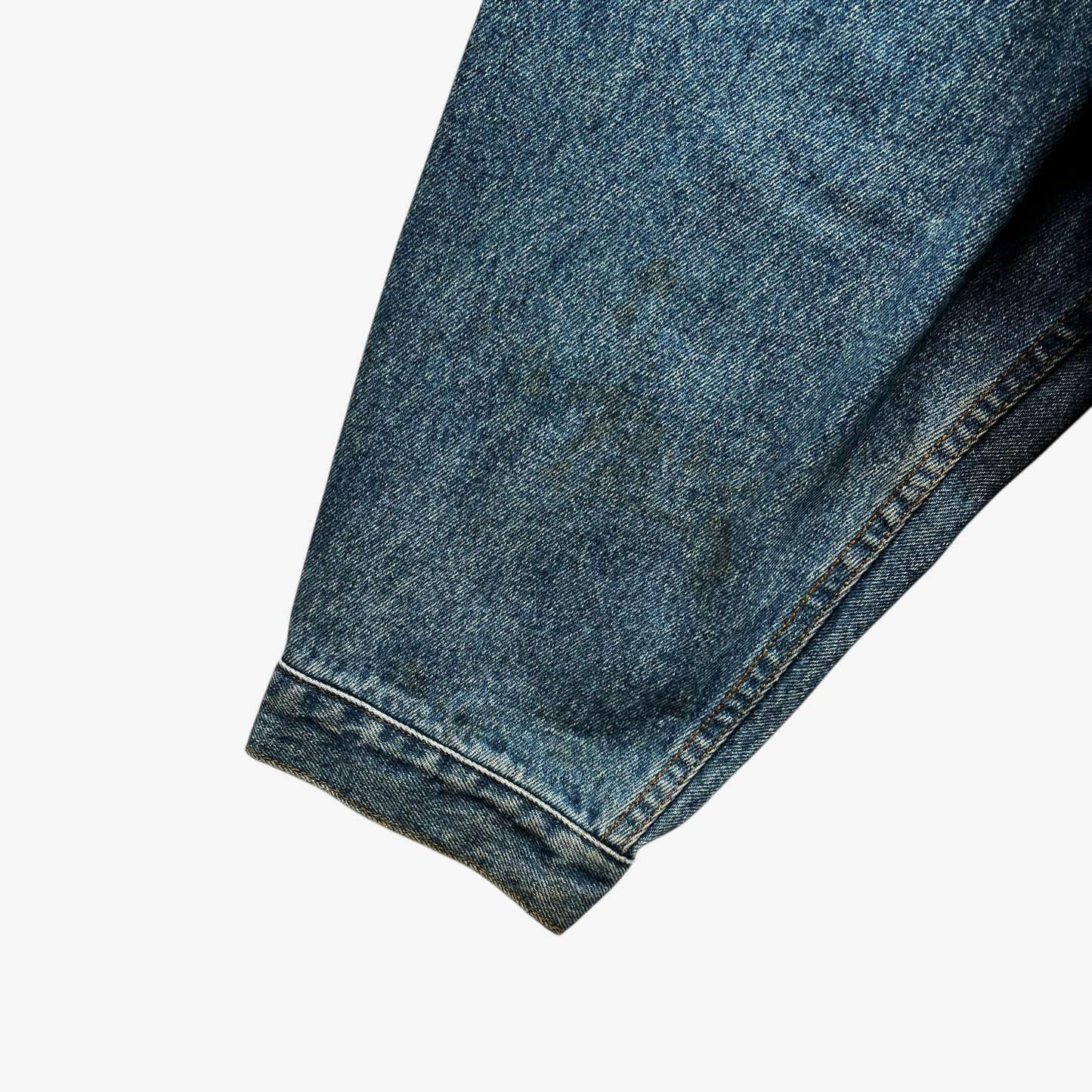 Cuff of men's vintage 90s Timberland blue denim jacket with leather collar and Looney Tunes Marvin Martian print.