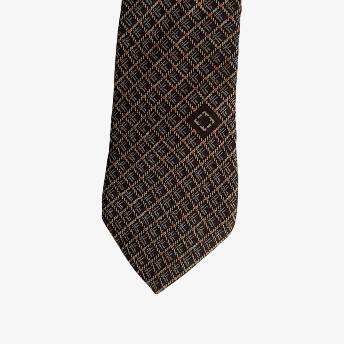 Close up of geometric abstract F initial print on a vintage 90s Salvatore Ferragamo brown silk tie.