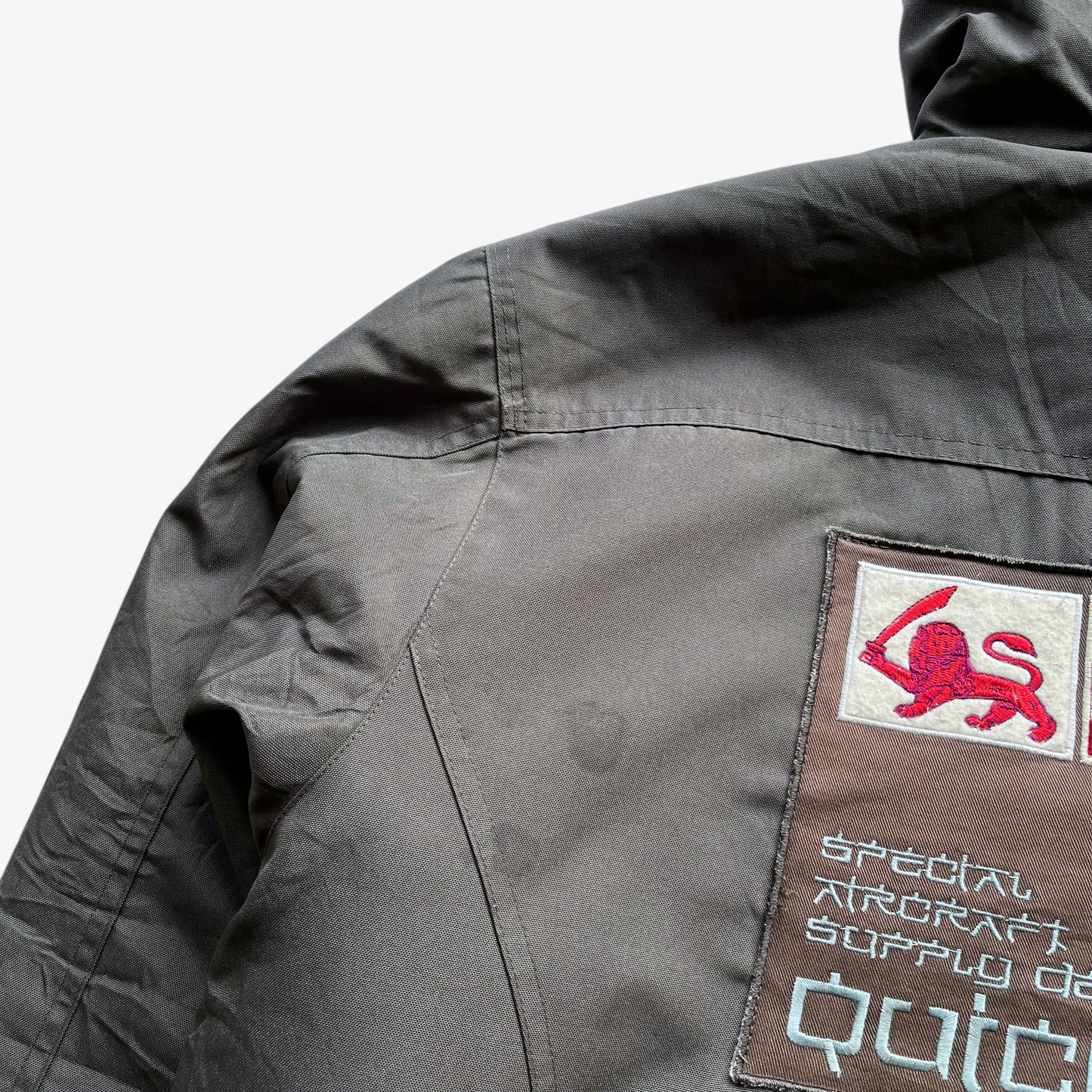 Patina on men's vintage Y2K Quickshark special aircraft supply grey utility jacket with back spell out.