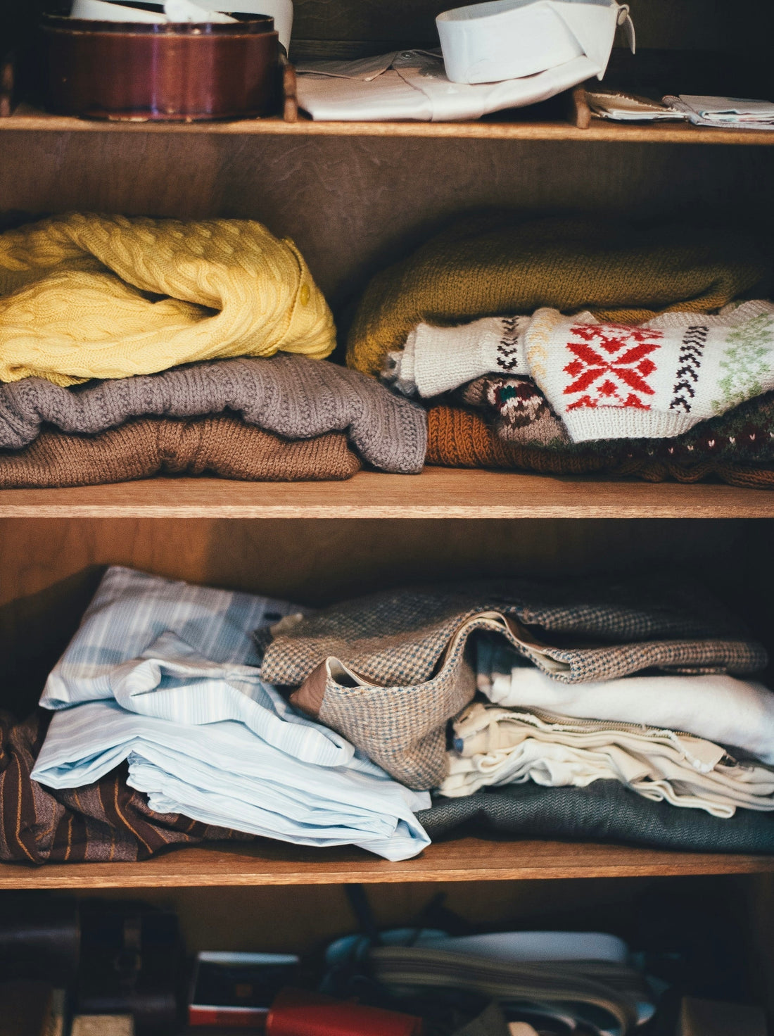 Folded vintage brown wool knitted jumpers and blue striped shirts
