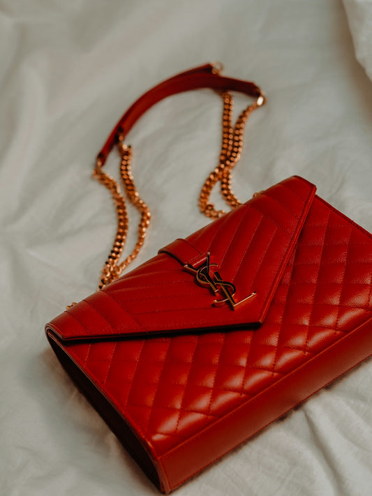 Close up of vintage Y2K Yves Saint Laurent red quilted leather handbag with YSL logo clasp.
