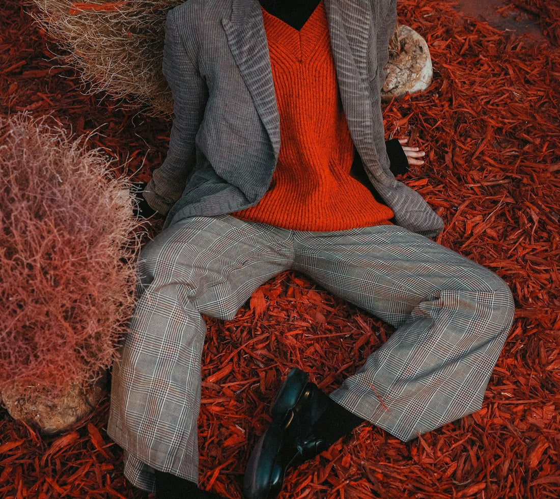 Close up of a female model wearing a vintage 80s red wool v-neck jumper and a 90s men's grey tweed suit.