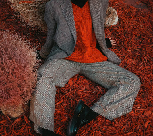 Close up of a female model wearing a vintage 80s red wool v-neck jumper and a 90s men's grey tweed suit.