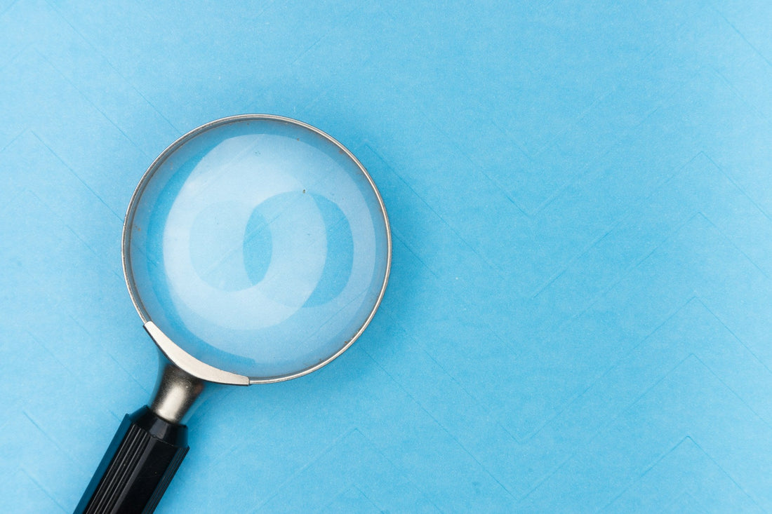 Close up of a magnifying glass pressed against a blue background.