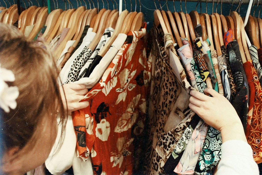 Close up of a woman model searching through ranks for vintage 90s Hawaiian shirts.
