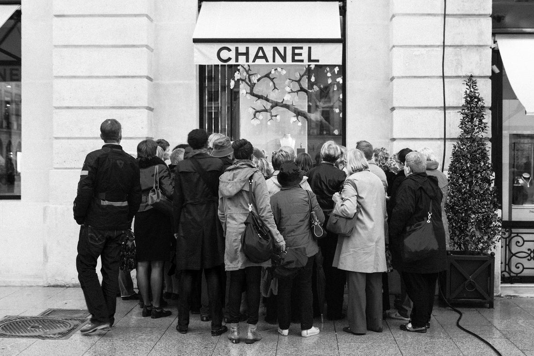 Rows of fashionable people waiting outside a vintage Chanel store in France.