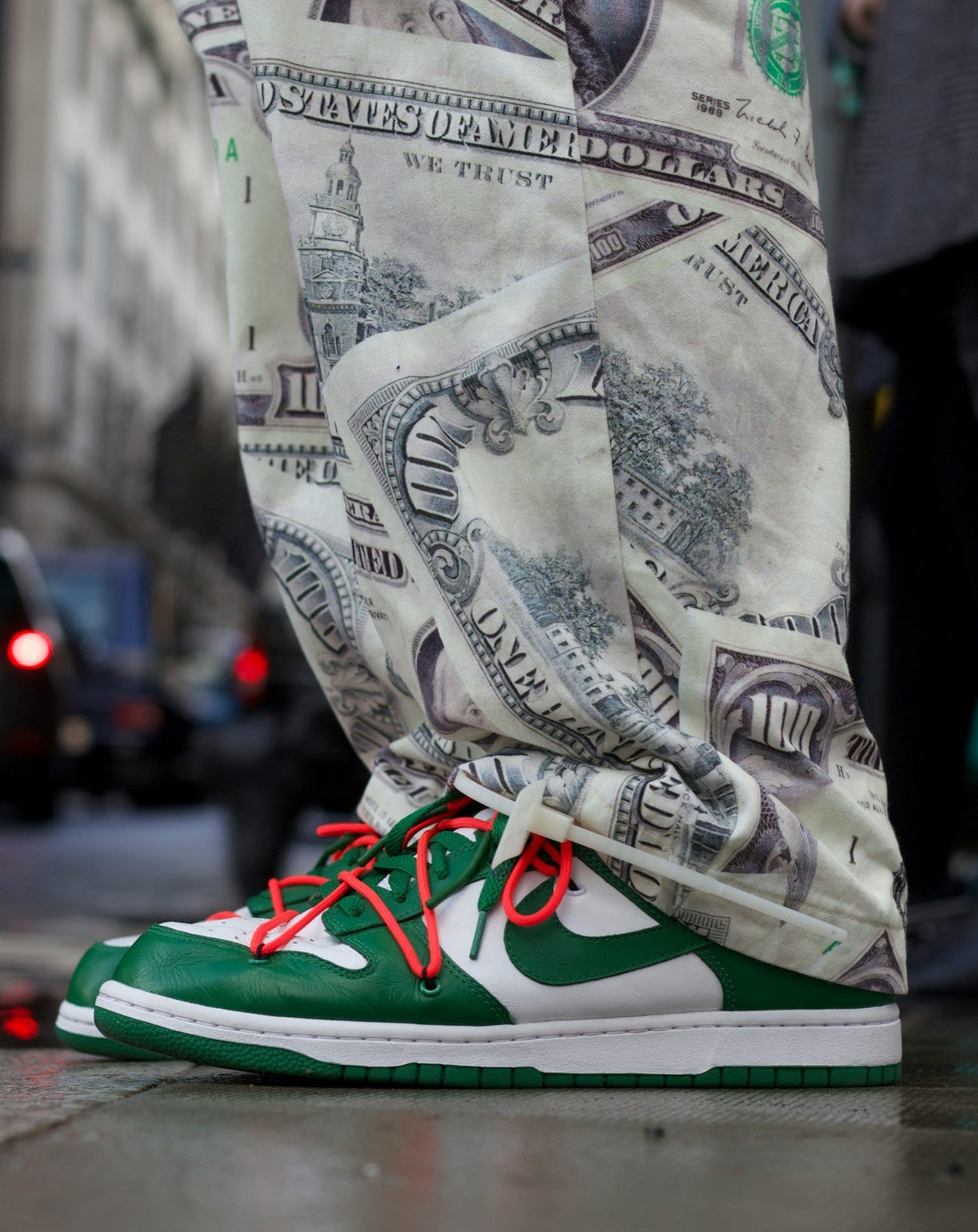 Close up of dollar note patterned trousers with retro nike green leather trainers.