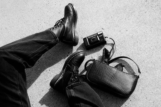 Close up of modelled vintage black jeans and a designer leather handbag.