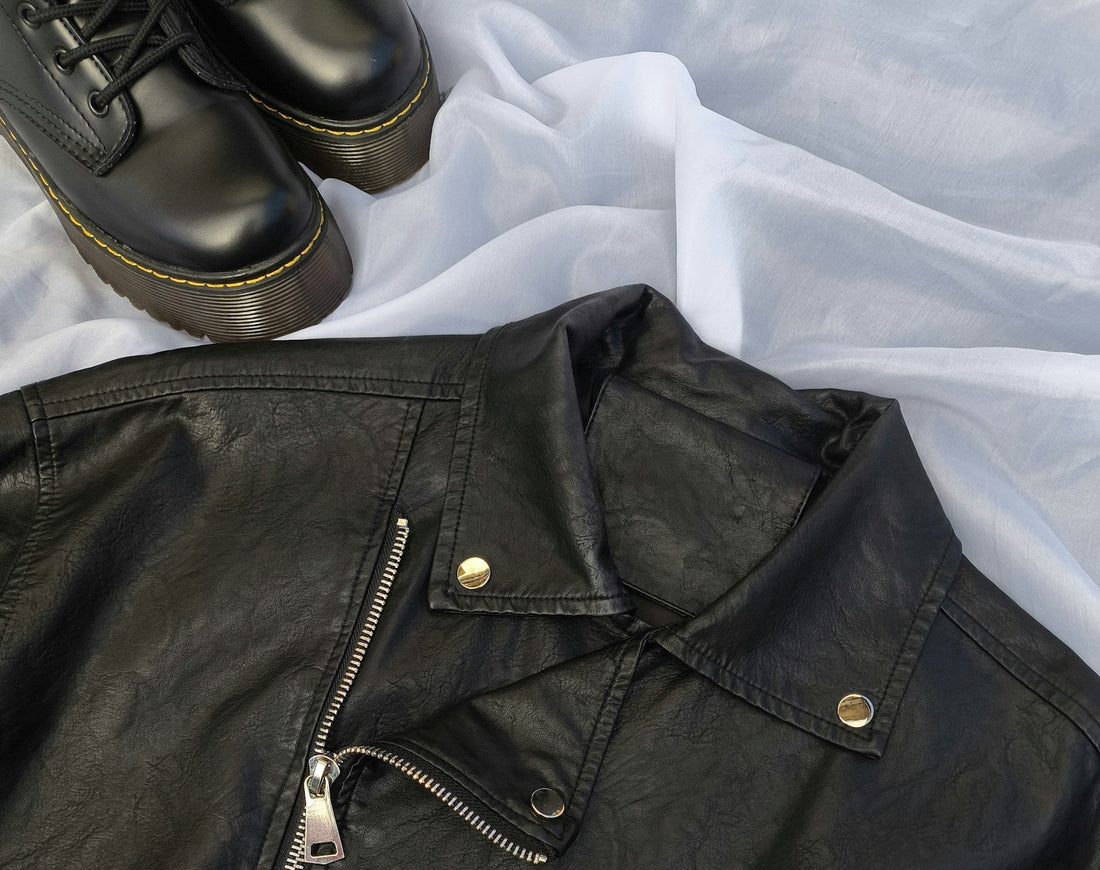 Close up of a men's vintage 90s black leather biker jacket and a pair of leather Dr Martens shoes.