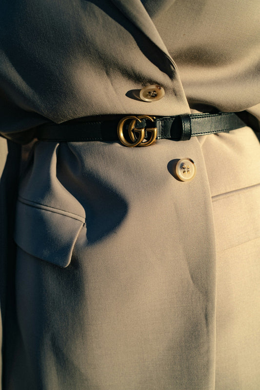 Vintage black Gucci belt with interlocking GG wrapped around a women's beige cotton coat
