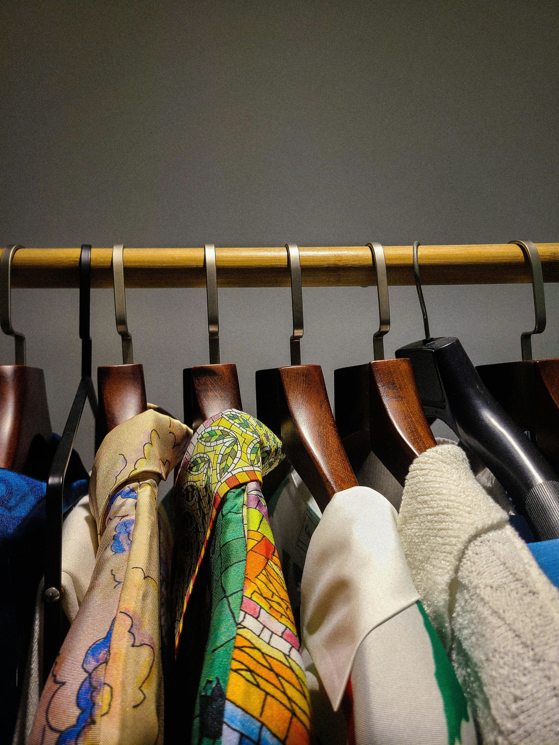 Gold rail lined with vintage designer clothing, including patterned silk shirts and wool coats