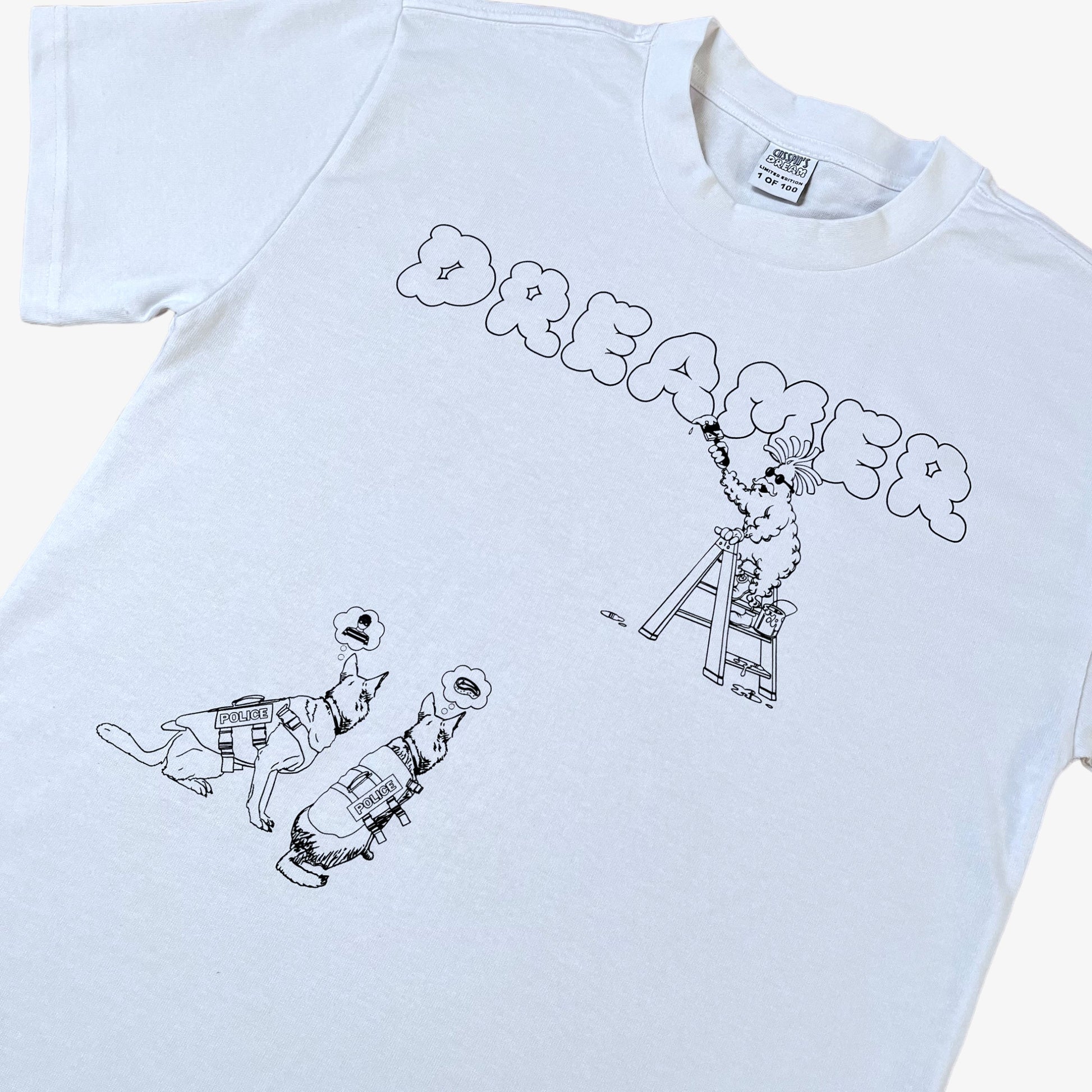 A white 100% organic cotton t-shirt with a graphic print featuring a Banksy styled cartoon character, police dogs and text that reads 'DREAMERS NEVER STOP creating'.