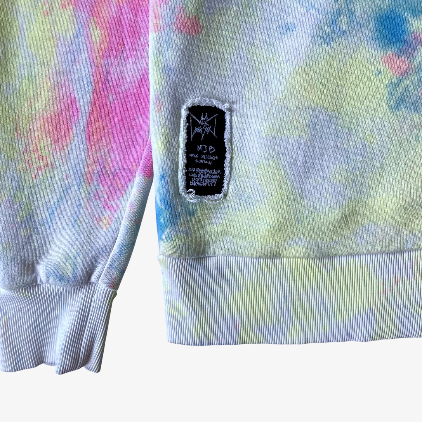 Colourful tie dye sweatshirt with a brand label on a white background.