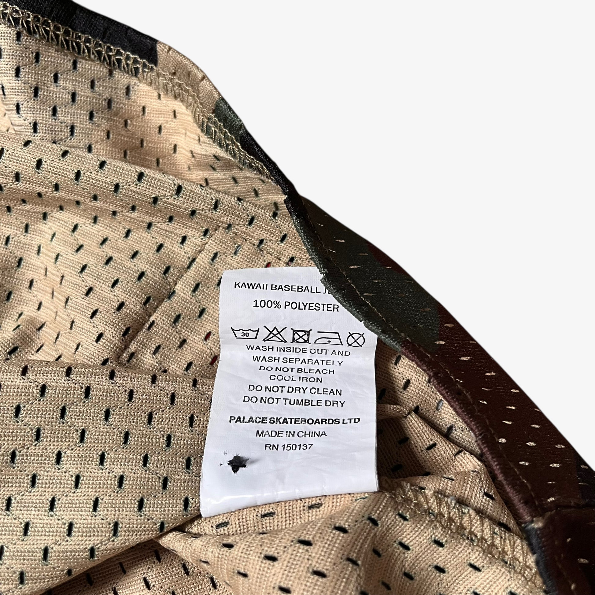Material label stitched inside of men's Palace kawaii green camouflage baseball jersey.