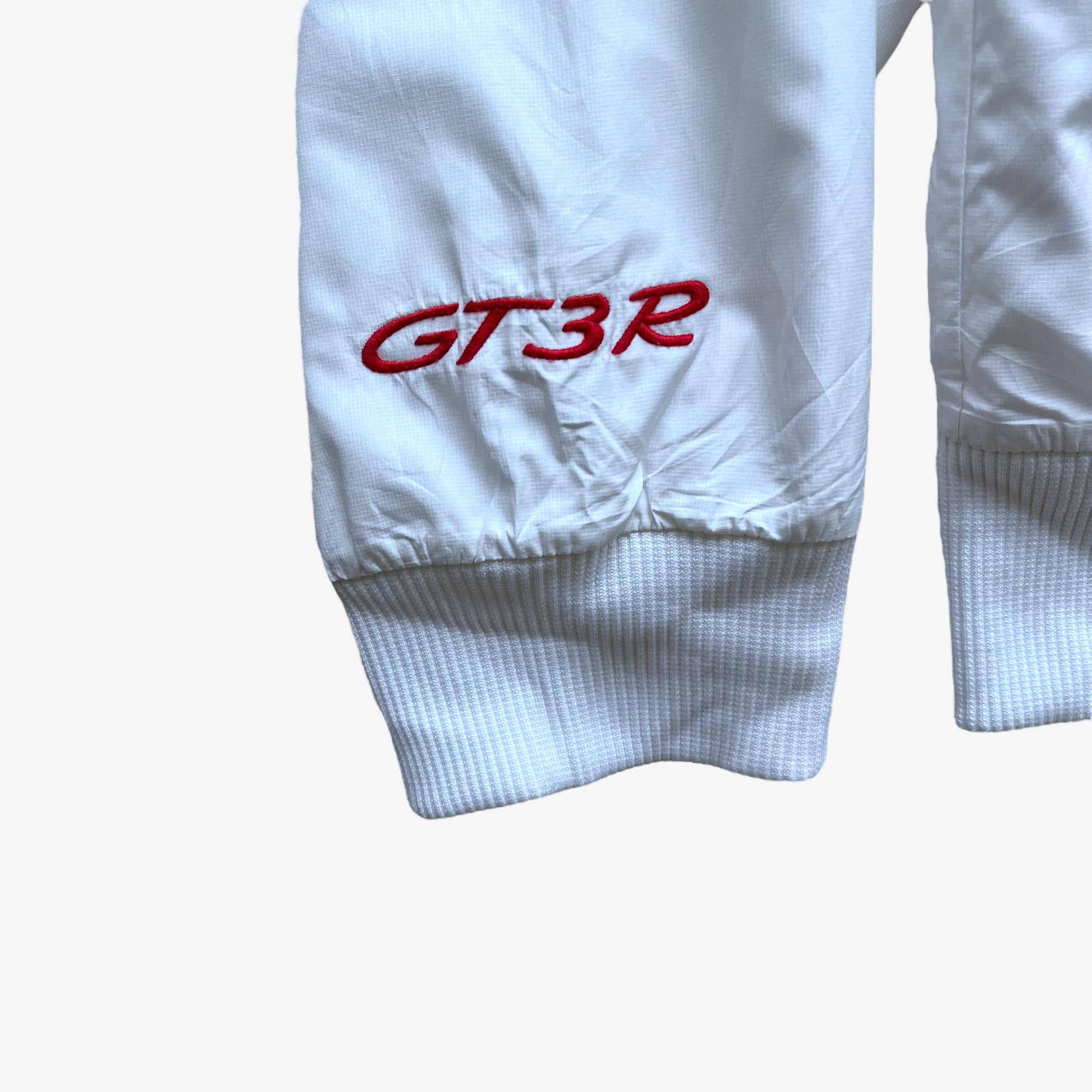 GT3R embroidered logo on the cuff of men's Puma Porsche 911 spell out print white driving jacket.
