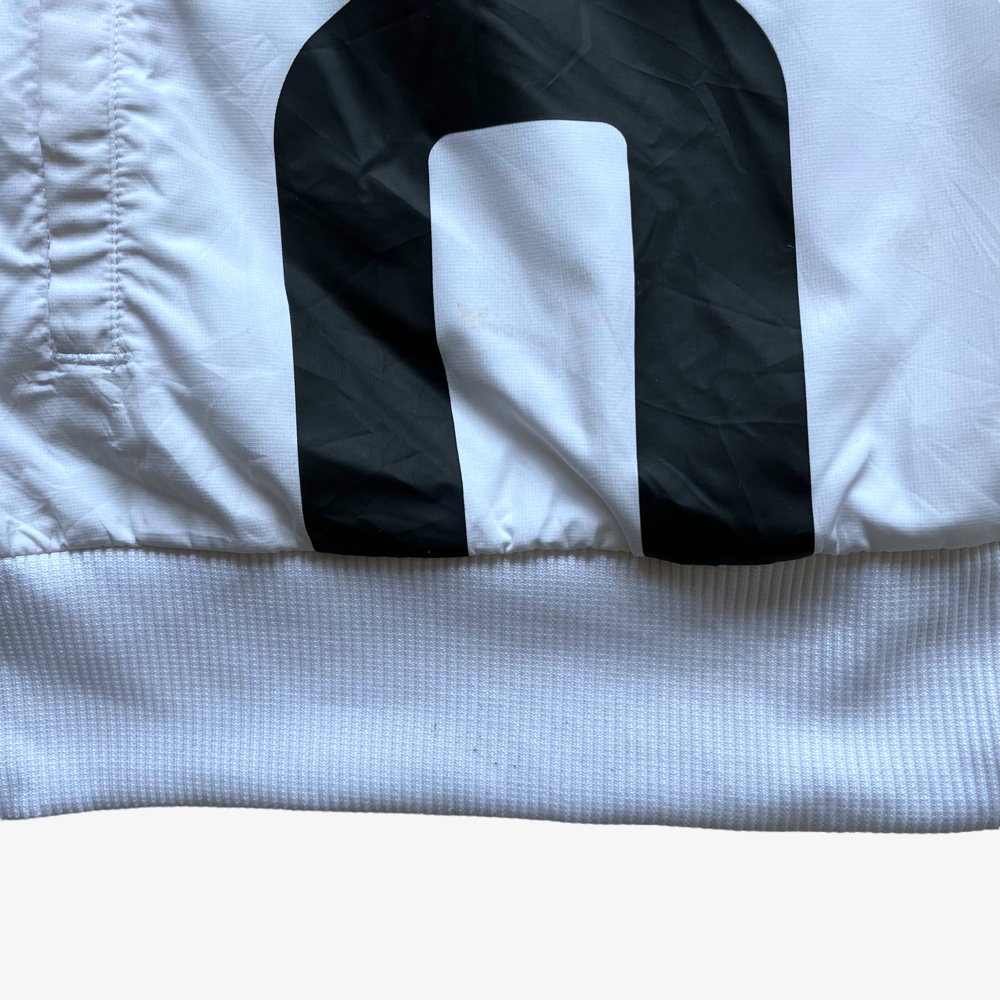 Hem of men's Puma Porsche 911 GT3R spell out print white driving jacket.