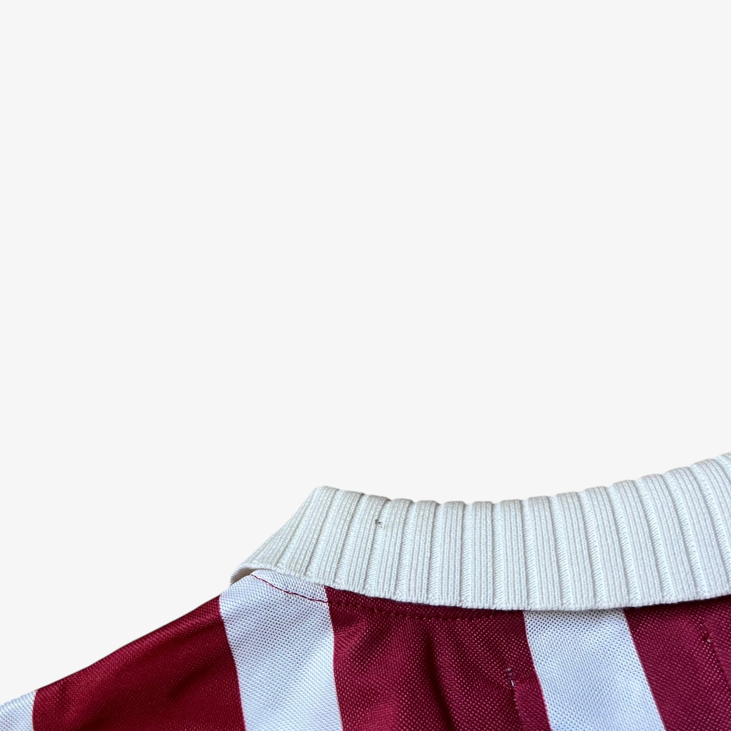 Wear on collar of men's Scuffers red and white striped football jersey.