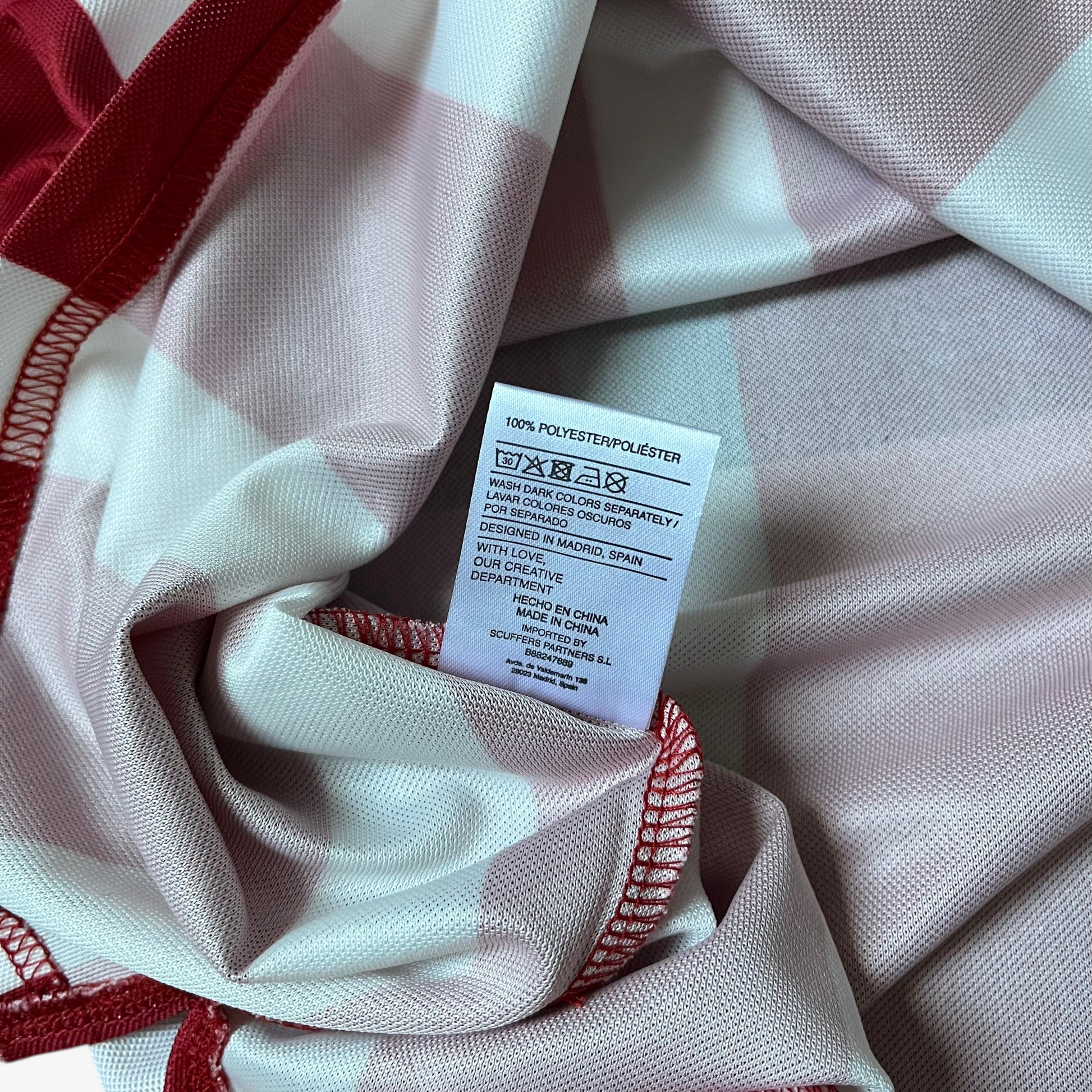 Internal label of men's Scuffers red and white striped football jersey.