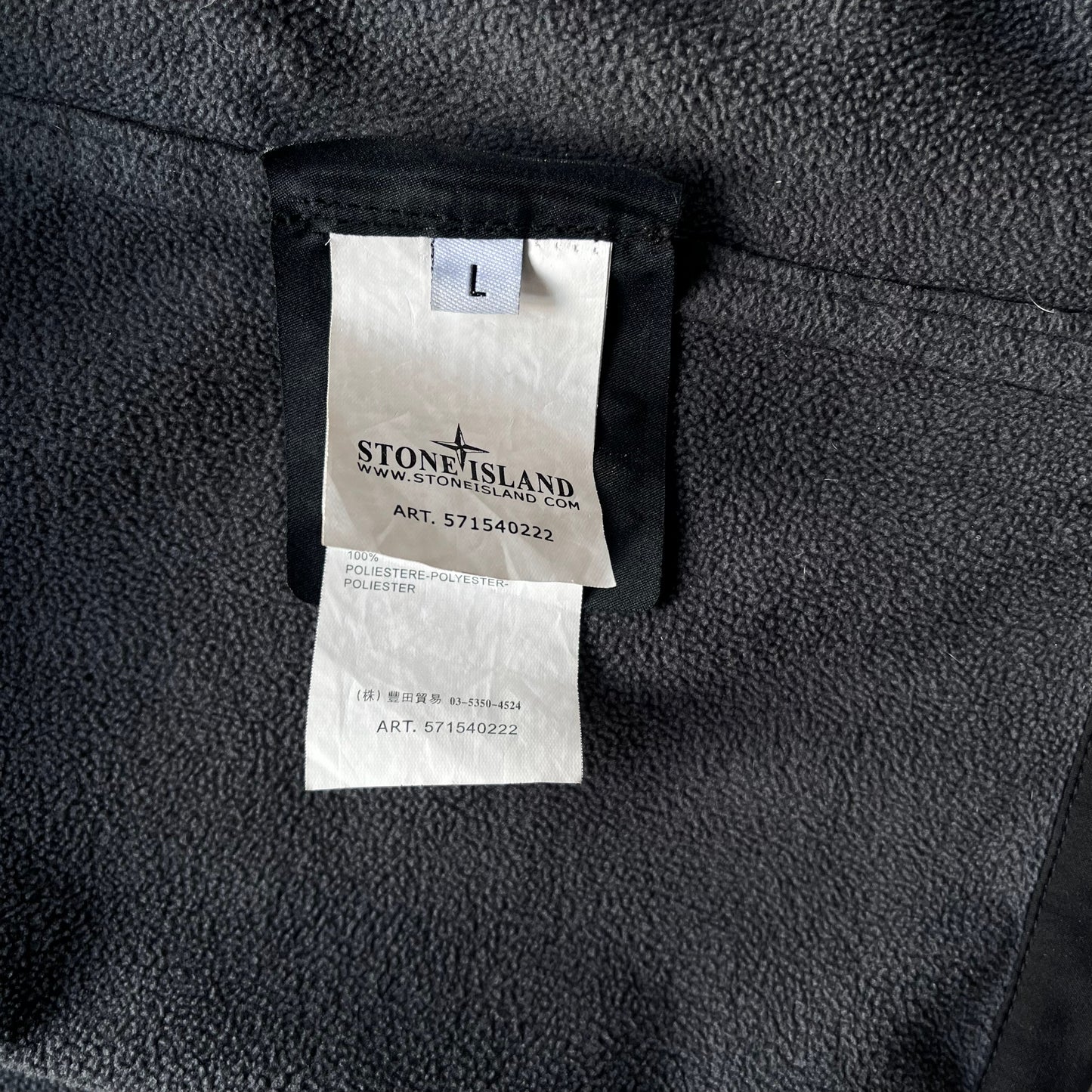 Art 571540222 inside label of men's Stone Island Soft Shell R black utility jacket with foldable hood.