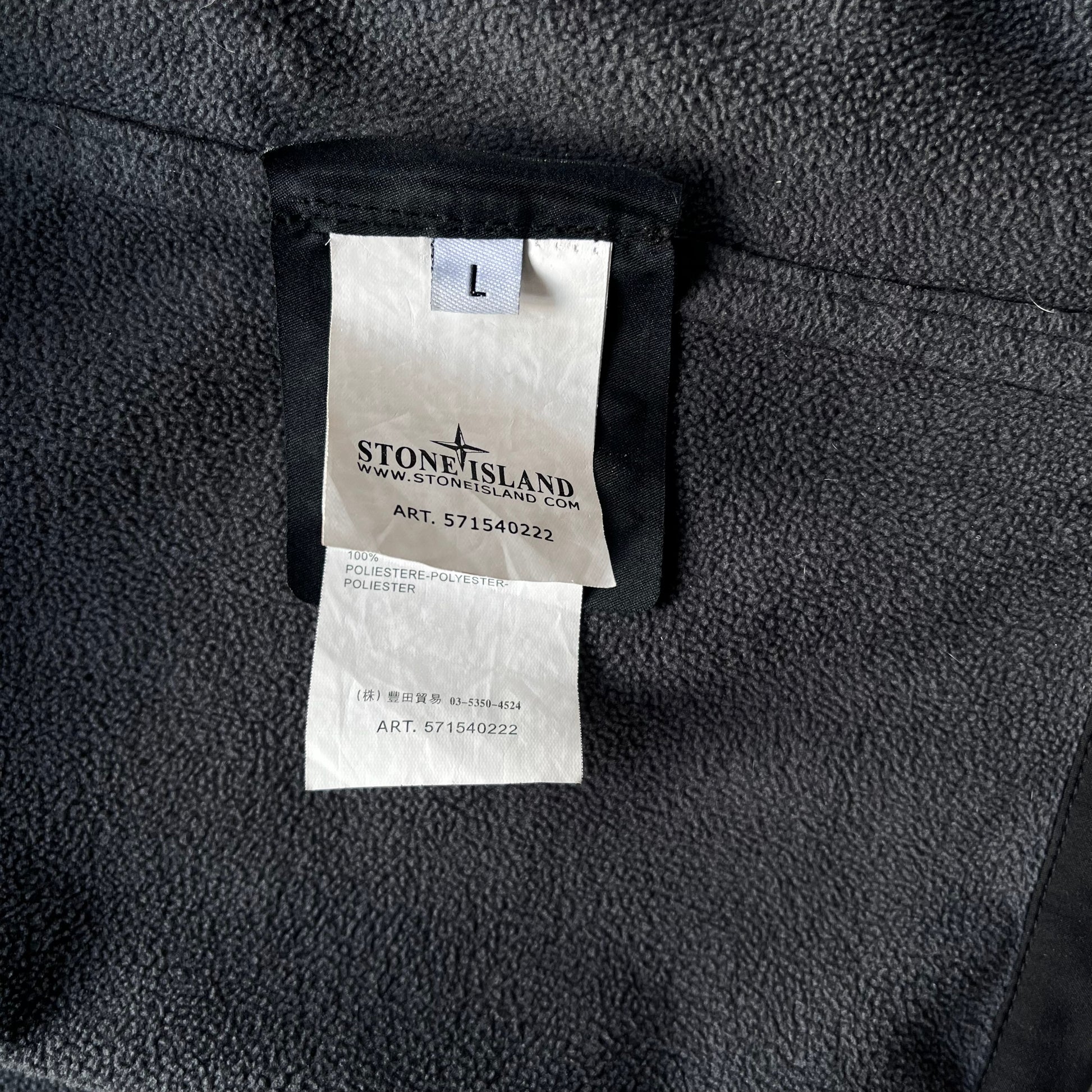 Art 571540222 inside label of men's Stone Island Soft Shell R black utility jacket with foldable hood.