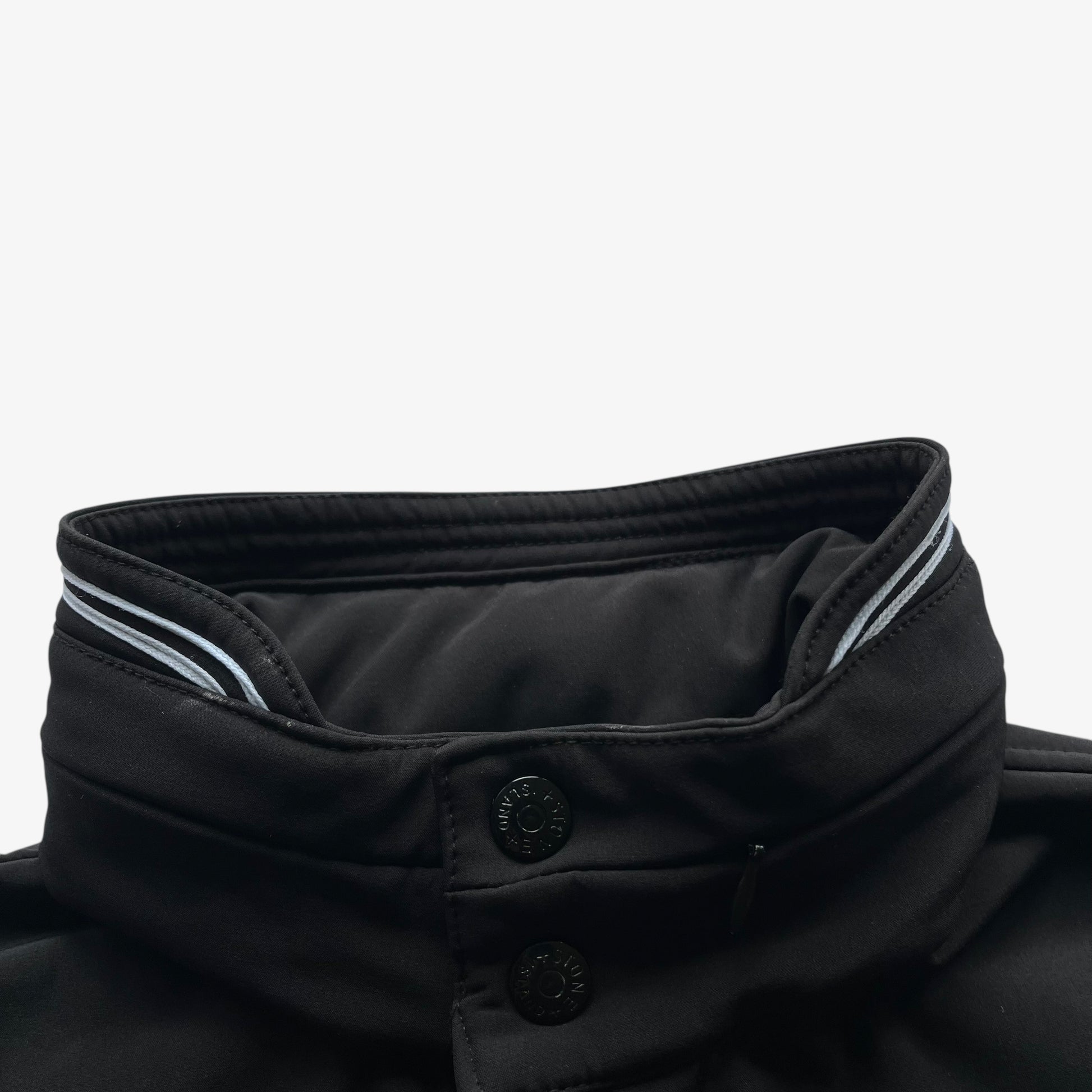 Engraved buttons of men's Stone Island Soft Shell R black utility jacket with foldable hood.