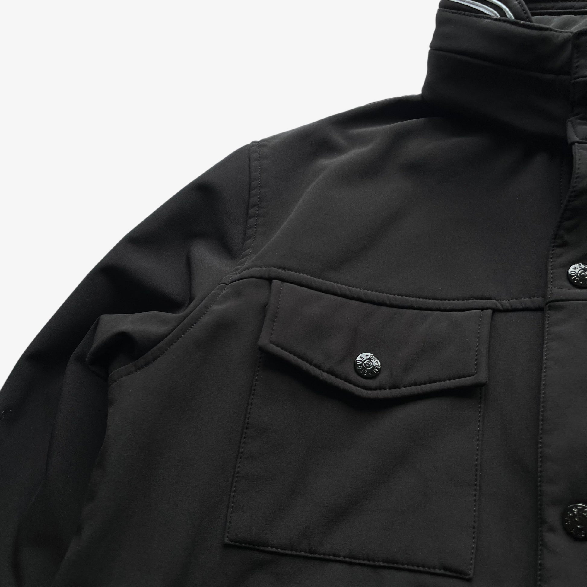 Patina on men's Stone Island Soft Shell R black utility jacket with foldable hood.