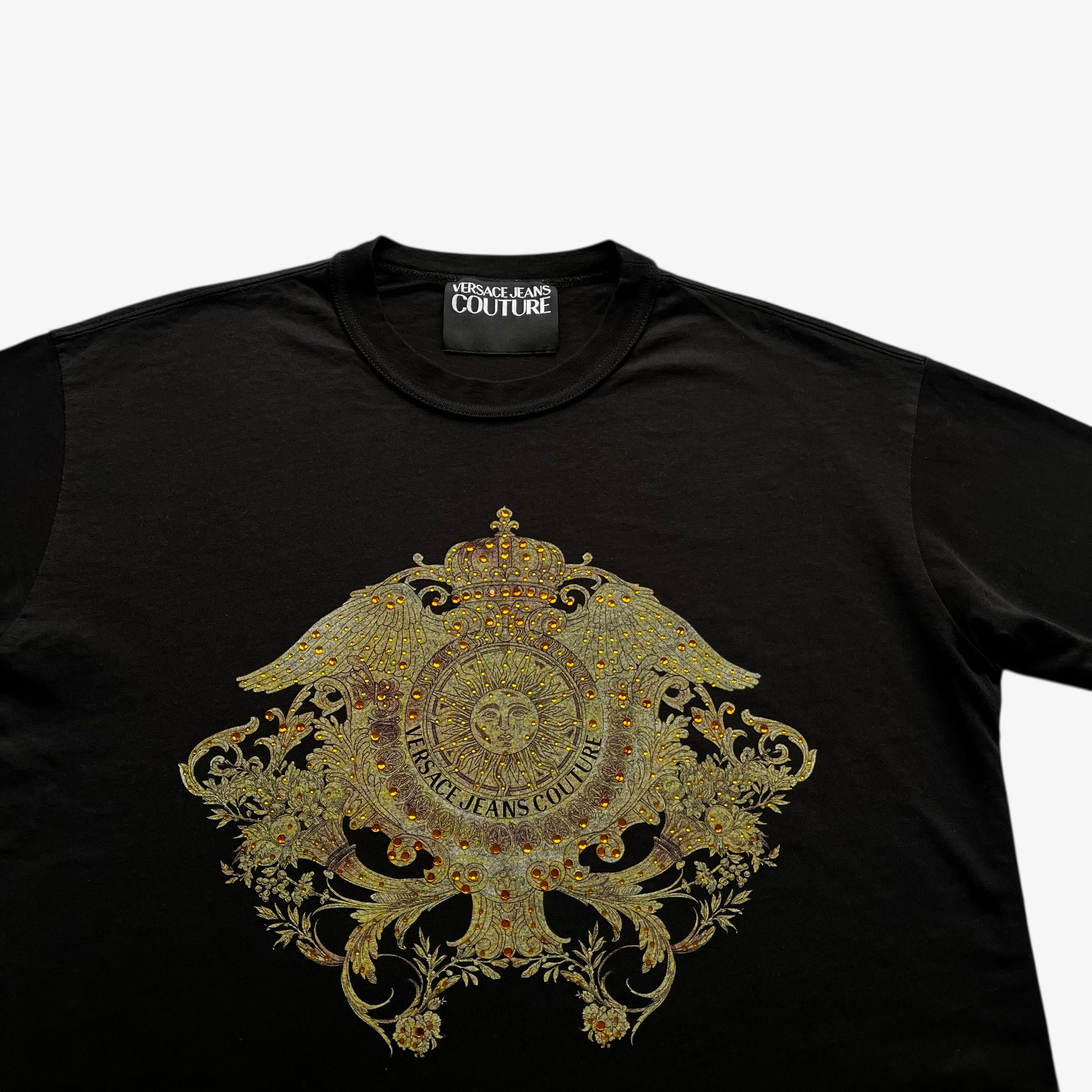 Close up of rhinestone baroque sun face print on men's Versace Jeans Couture black t-shirt.