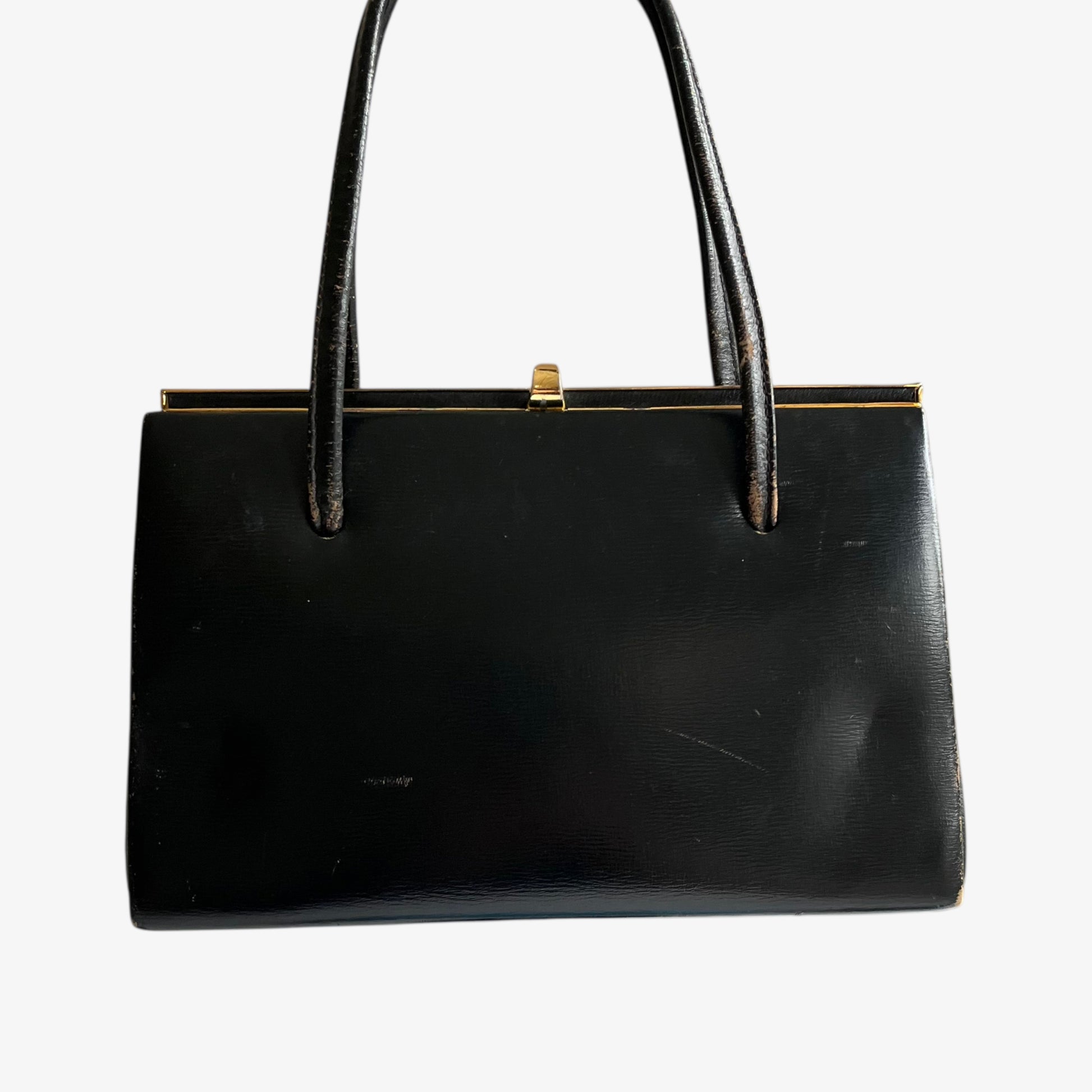 Back of a vintage 1950s black leather frame bag with a gold clasp on a white background.