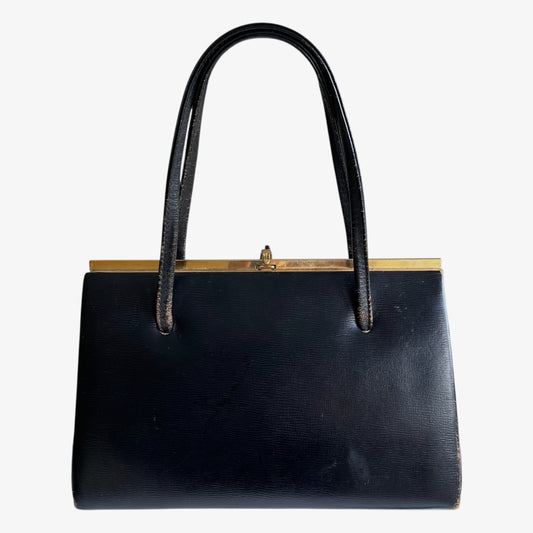 Vintage 1950s black leather frame bag with a gold clasp on a white background.