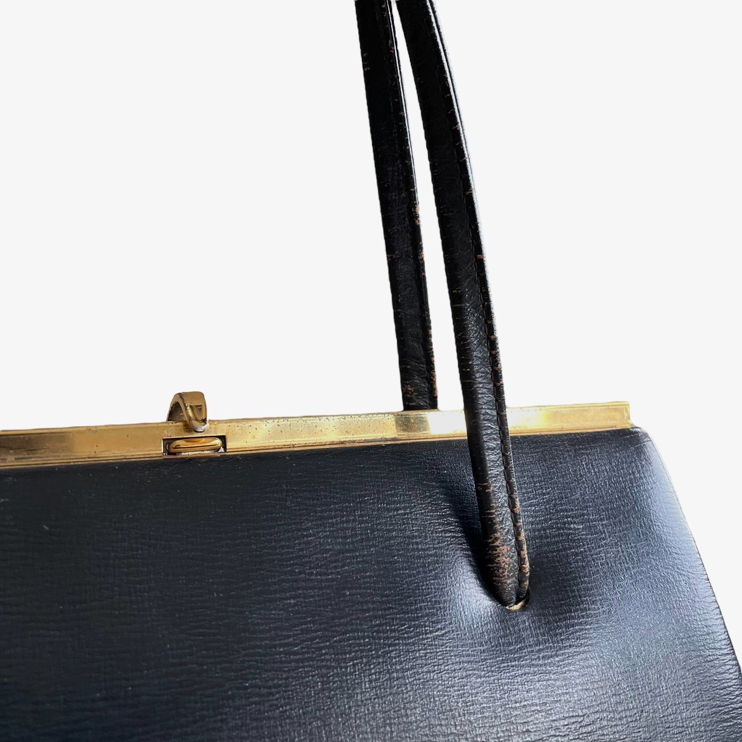 Close up of gold frame on a vintage 1950s black leather frame bag.