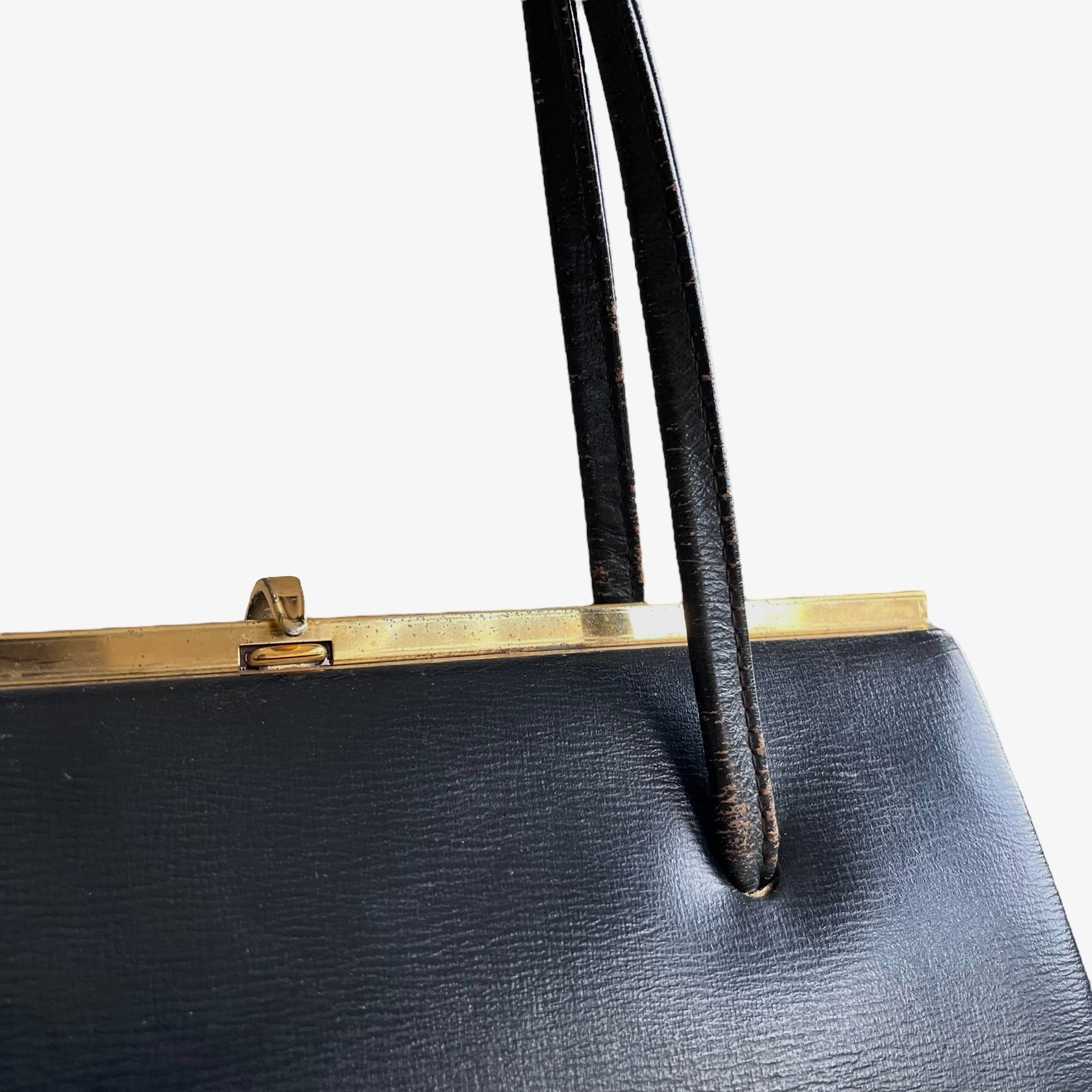 Close up of gold frame on a vintage 1950s black leather frame bag.