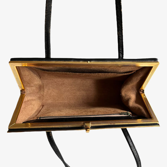 Inside suede lining of a vintage 1950s black leather frame bag with a gold clasp.