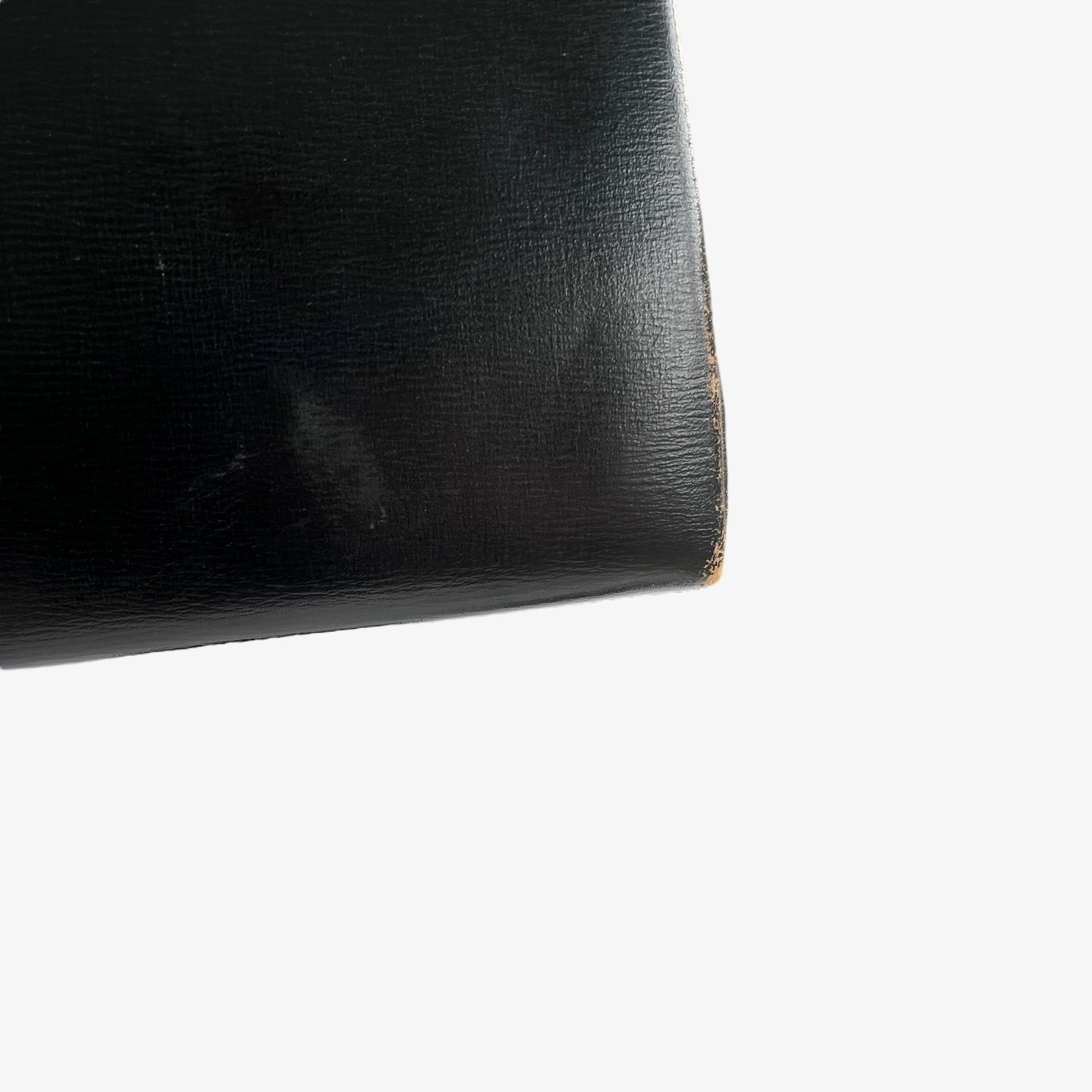 Faded leather on the corner of a vintage 1950s black frame bag.