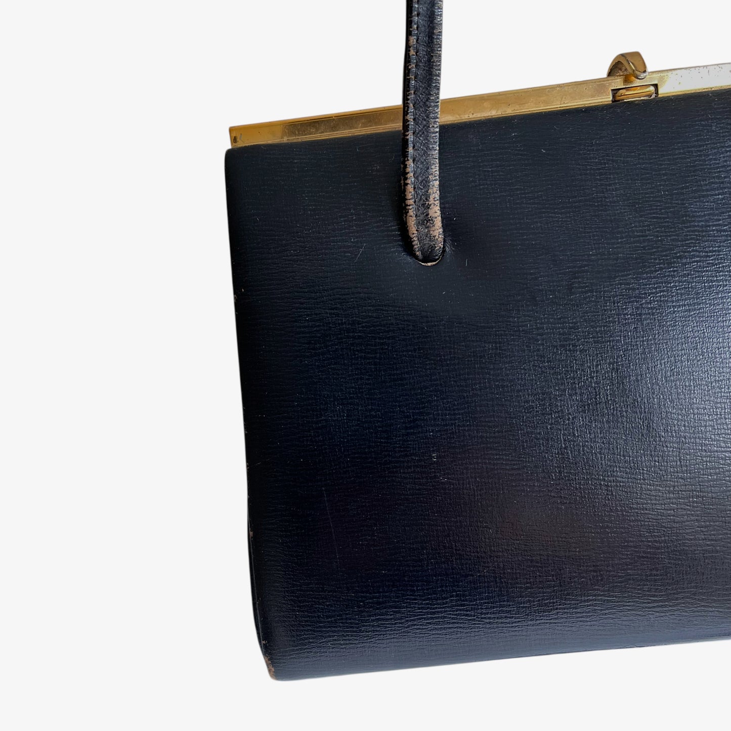 Patina on the handles of a vintage 1950s black leather frame bag.