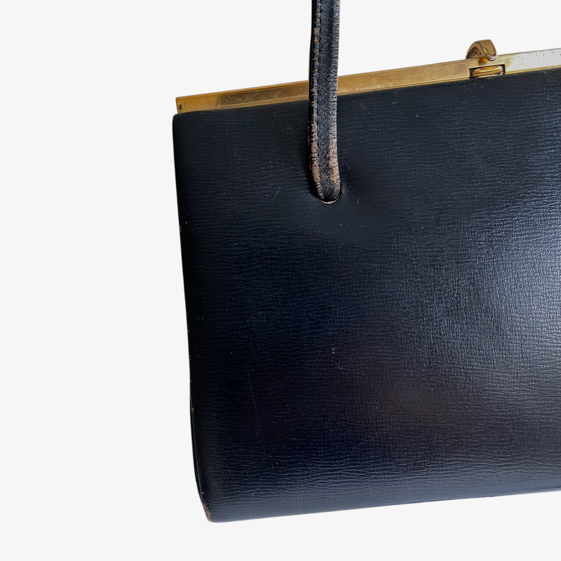 Patina on the handles of a vintage 1950s black leather frame bag.