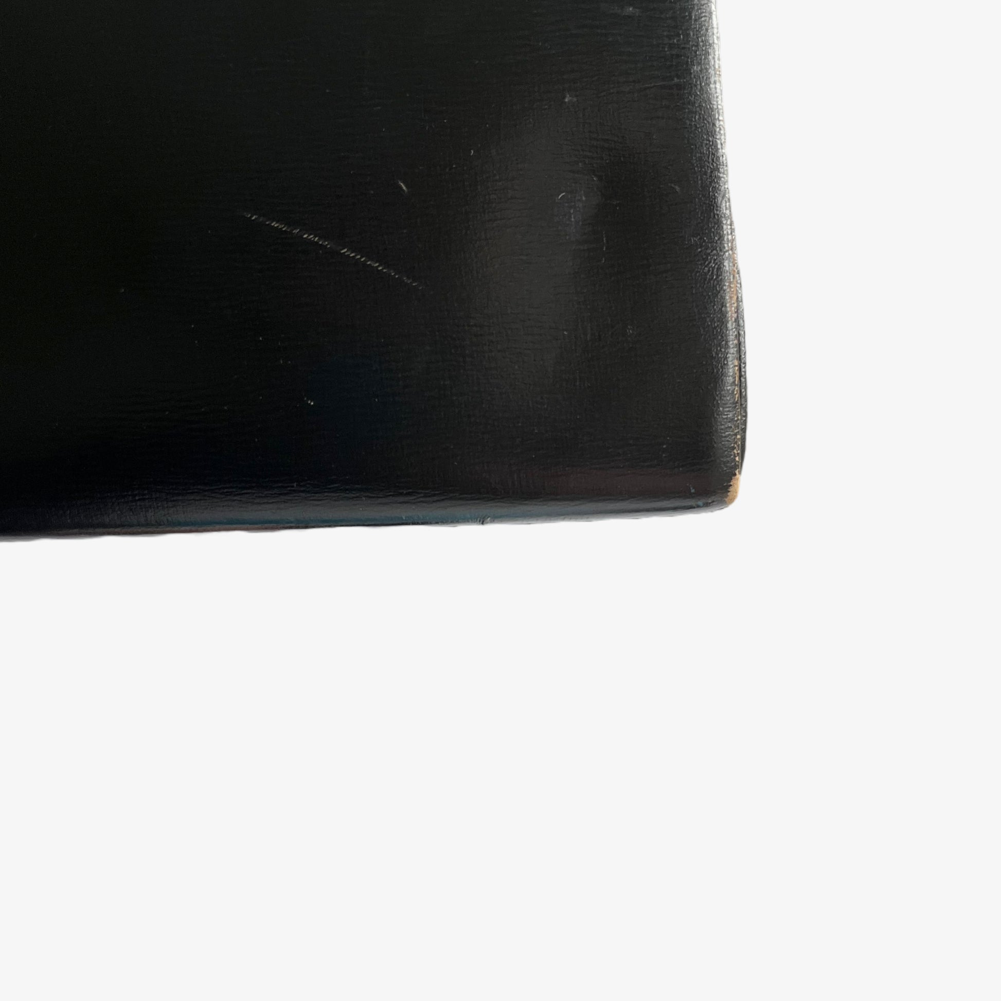 Close up of the scuff on the back of a vintage 1950s black leather frame bag.