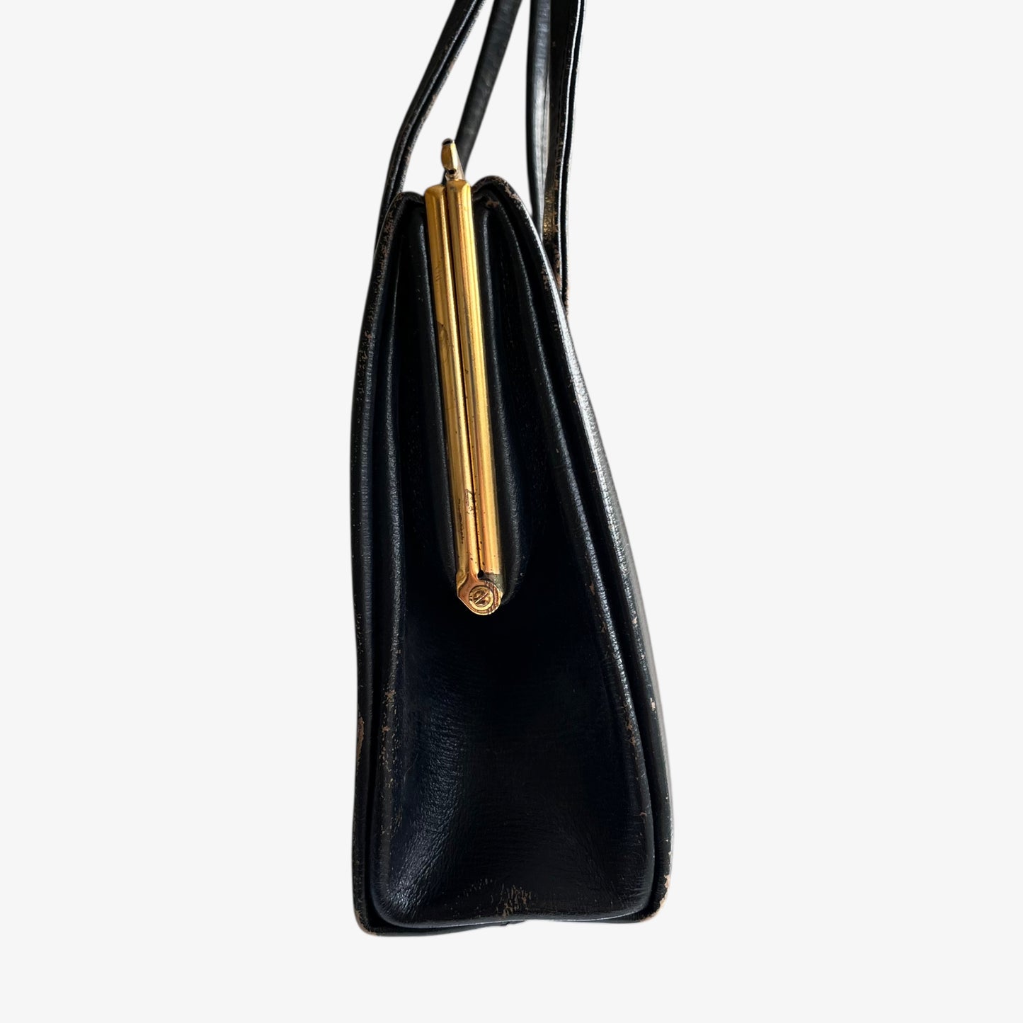 Side profile of a vintage 1950s black leather frame bag with a gold clasp.
