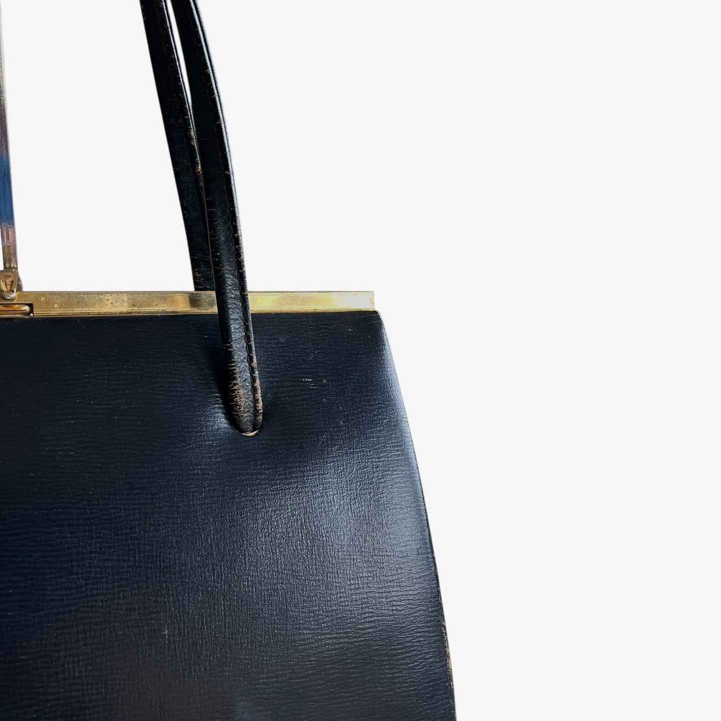 Wear on the straps of a vintage 1950s black leather frame bag.