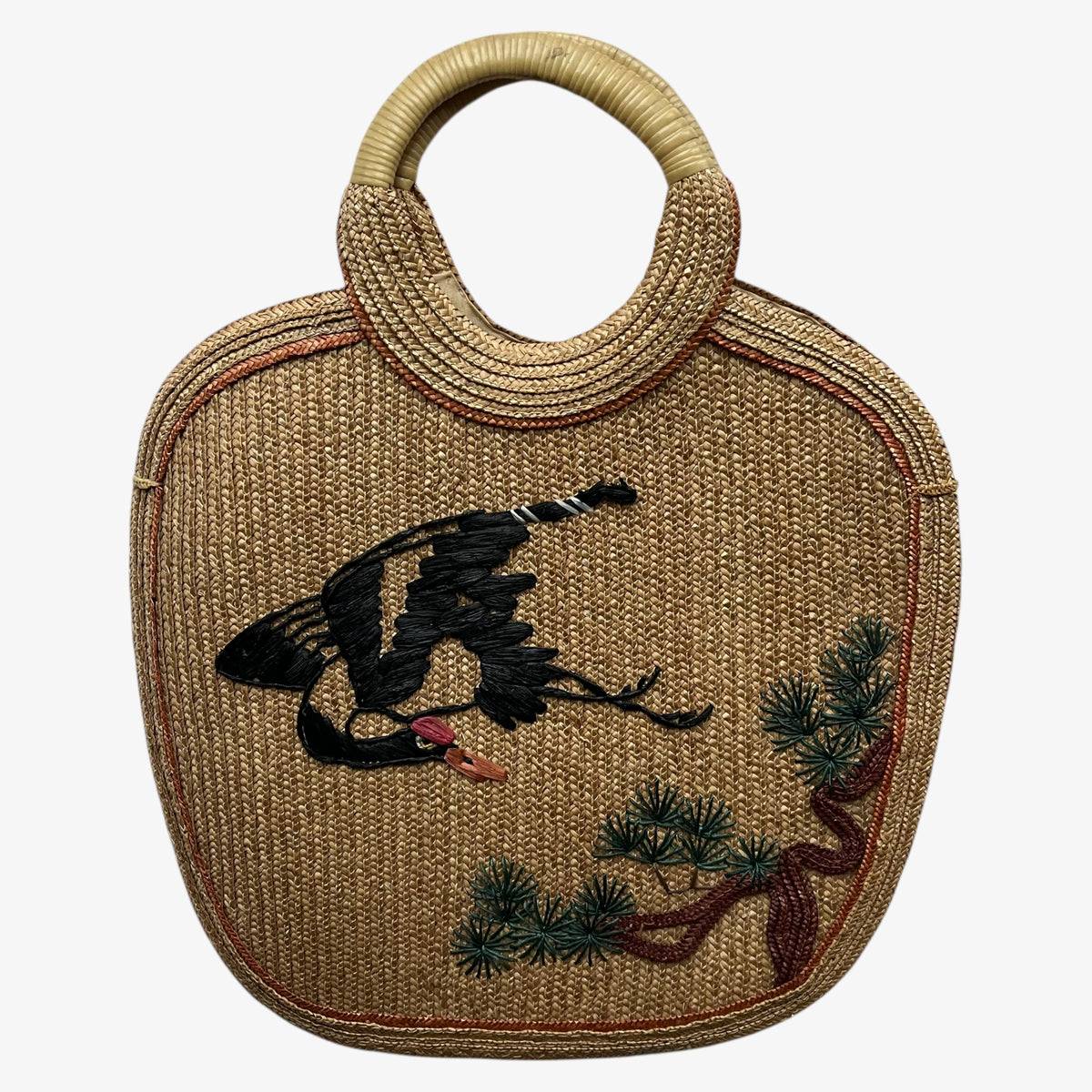 Vintage 1950s crane and tree embroidered brown raffia tote bag on a white background.