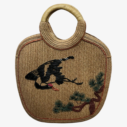Vintage 1950s crane and tree embroidered brown raffia tote bag on a white background.