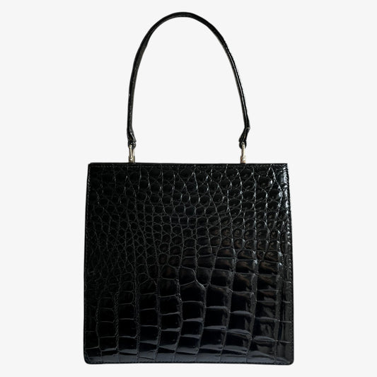 Vintage 1950s crocodile embossed black leather shoulder bag on a white background.