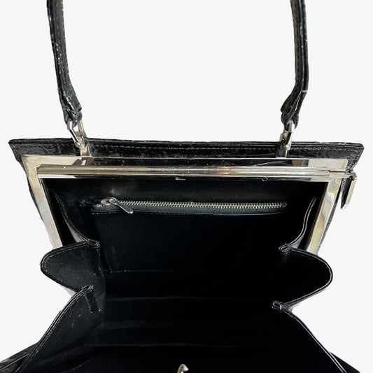 Close up of the zipped pocket inside of a vintage 1950s crocodile embossed black leather shoulder bag.
