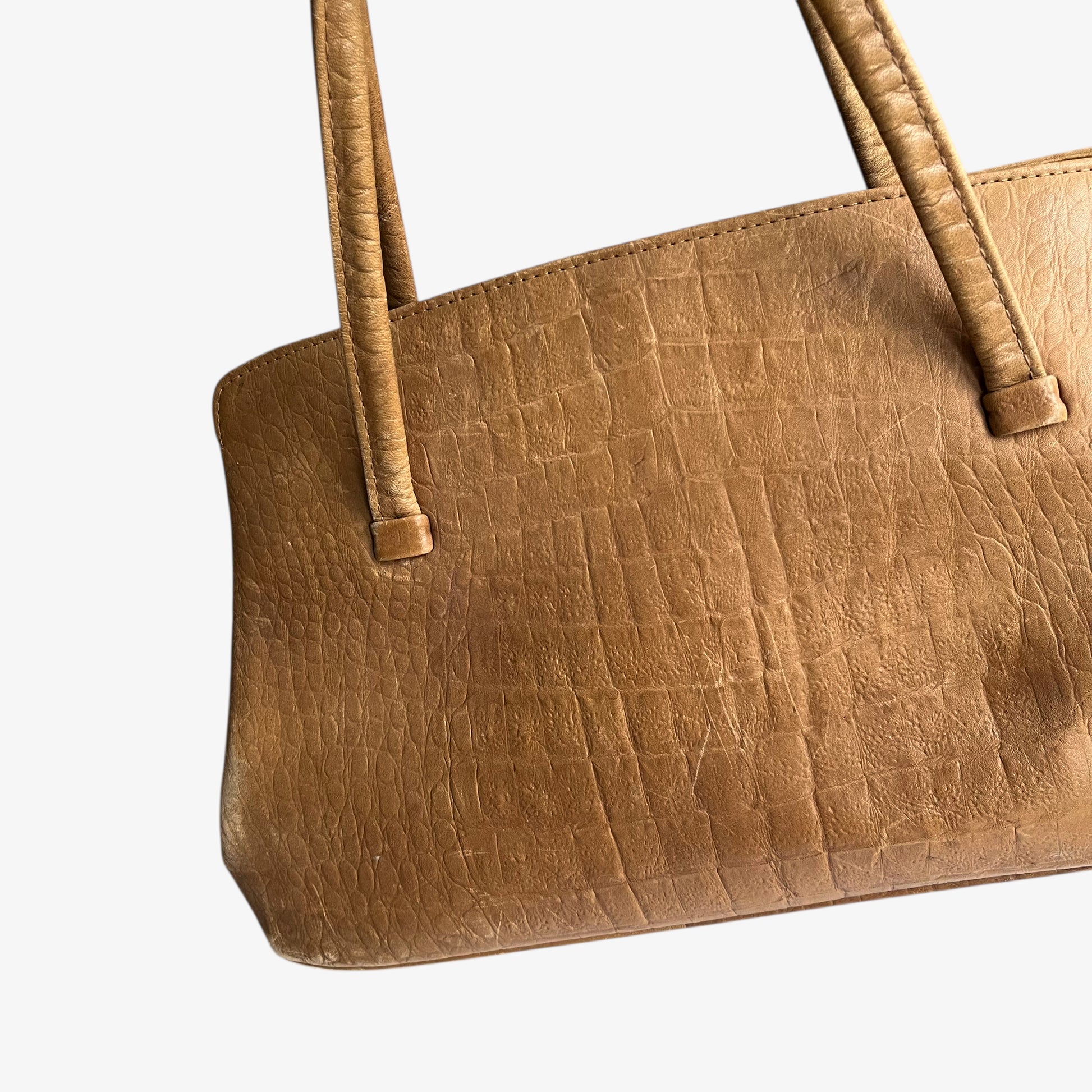 Close up of crocodile and alligator effect on a vintage 1950s brown leather shoulder bag.