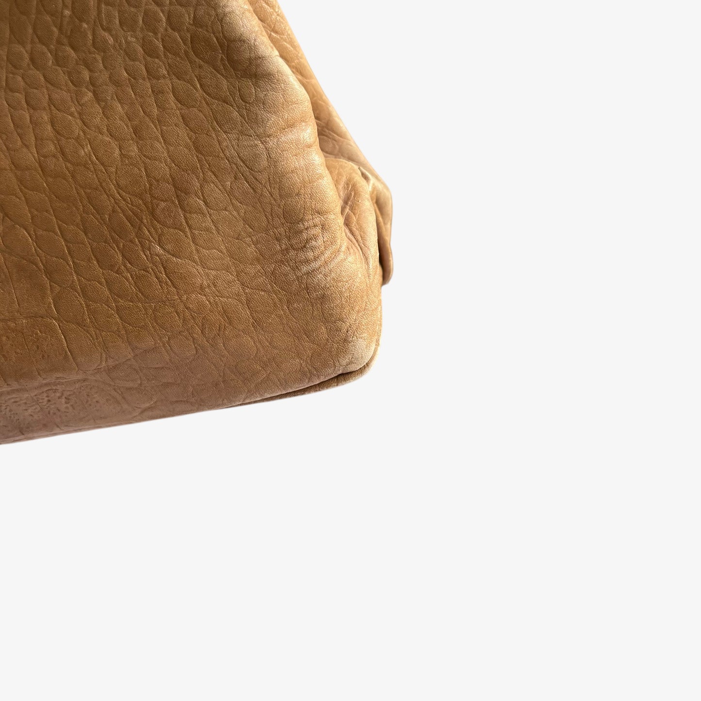 Fading patina on the corner of a vintage 1950s crocodile embossed light brown leather shoulder bag.